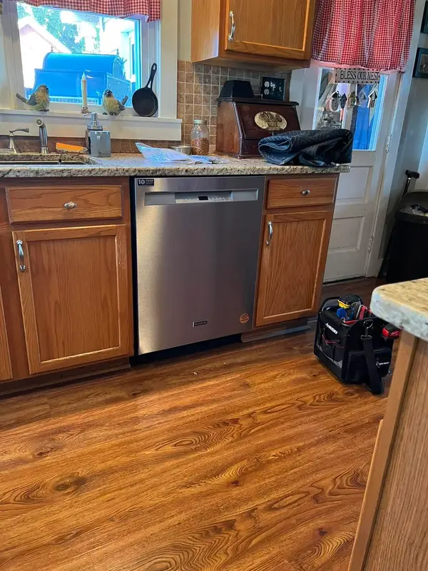 Stainless dishwasher fitted into oak cabinets