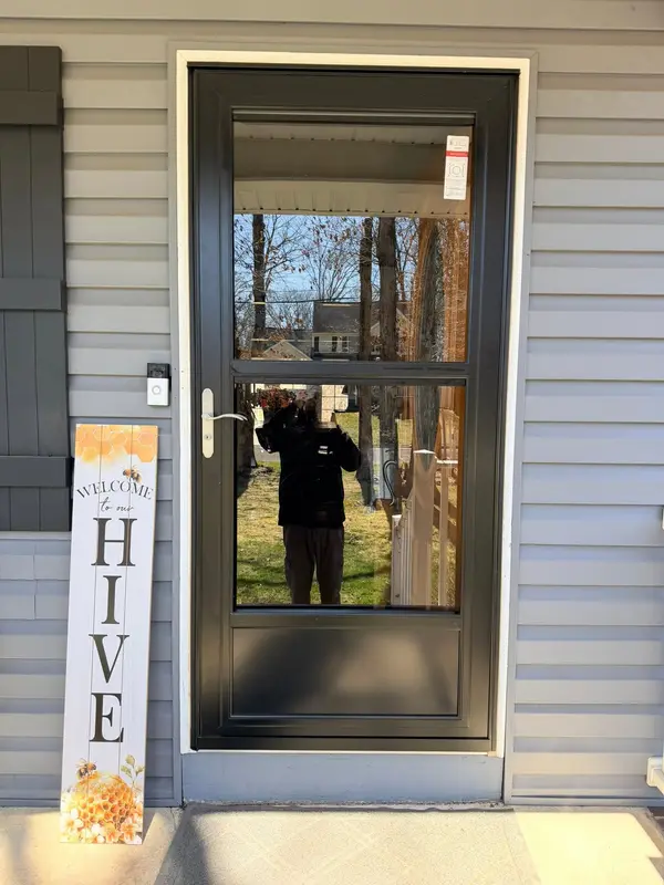 New black full-view storm door on a grey-sided house