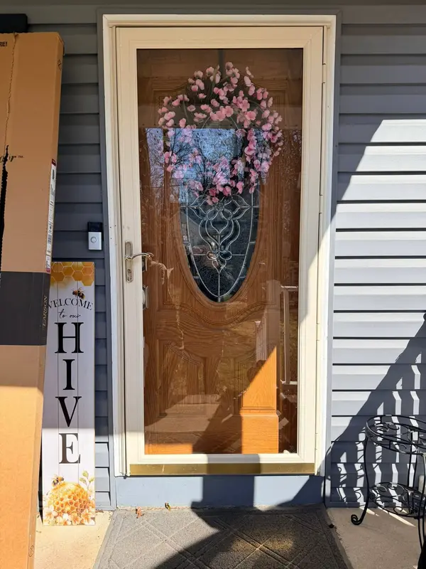 White full-view storm door over a decorative wood front door