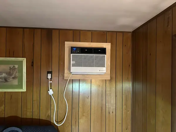 Through-the-wall AC unit framed into a wood-panelled wall